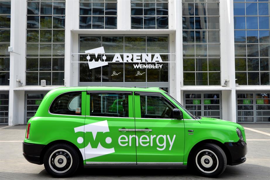 A black cab painted green with the OVO Energy logo on the side outside the OVO Arena